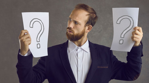 Puzzled businessman holding two question marks asking himself what decision to take