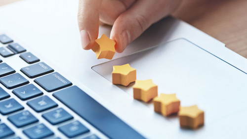 hand gives five stars rating as product feedback with laptop