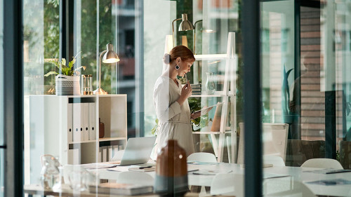 A modern office, building interior and a businesswoman doing online research on a tablet or looking at files. Female inside her corporate workplace architecture indoors preparing for a presentation.
