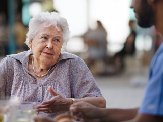 Caregiver having breakfast with his client at cafe.