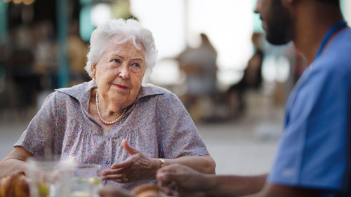 Caregiver having breakfast with his client at cafe.