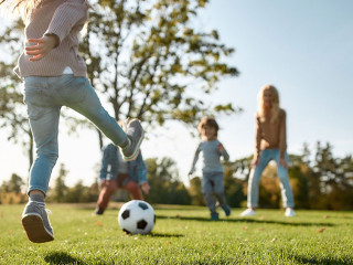 Where family fun begins. Happy family playing with a ball on meadow