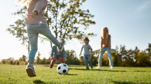 Where family fun begins. Happy family playing with a ball on meadow