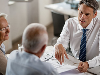 Insurance agent consulting senior couple about  their financial reports on a meeting.