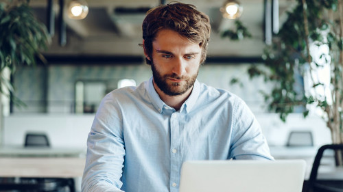 Businessman in shirt working on his laptop in an office