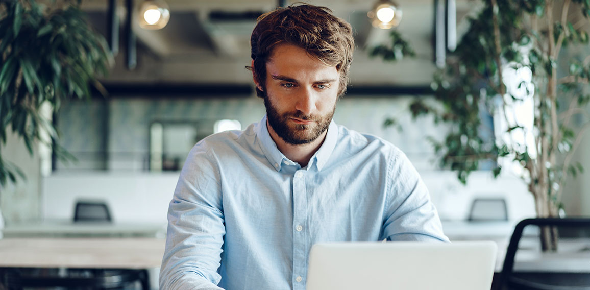 Businessman in shirt working on his laptop in an office