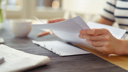 frau sitzt am küchentisch und liest einen brief