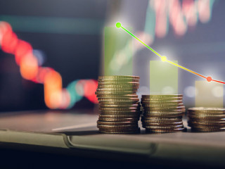 investment concept, stacked coins with a background monitor showing data graphs.