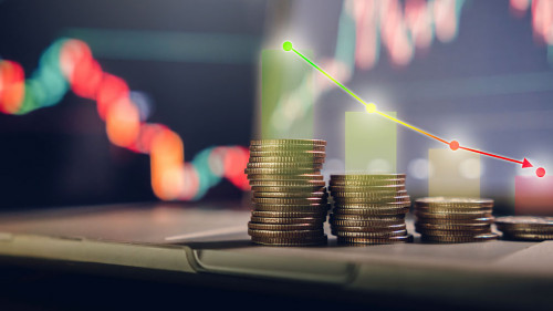 investment concept, stacked coins with a background monitor showing data graphs.