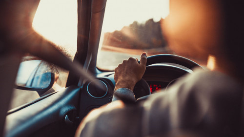 Man driving car, hand on steering wheel, looking at the road ahe