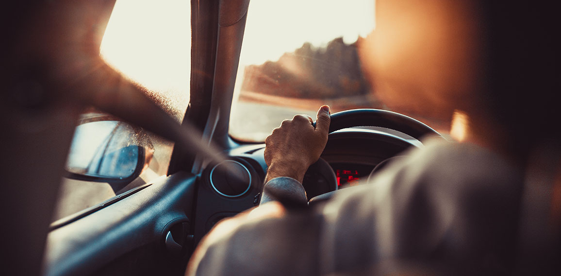 Man driving car, hand on steering wheel, looking at the road ahe