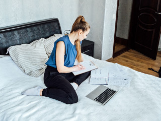 Job search concept, find your career. Young woman looking a job at online website by laptop computer sitting on bed at home.