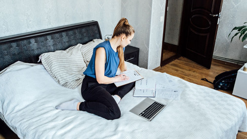 Job search concept, find your career. Young woman looking a job at online website by laptop computer sitting on bed at home.