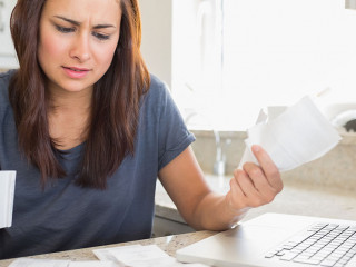 Young woman getting stressed over finances in kitchen