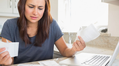 Young woman getting stressed over finances in kitchen