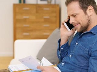 mann telefoniert und schaut mit ernstem gesicht auf unterlagen