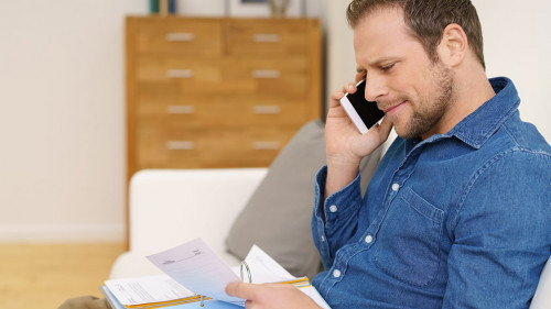 mann telefoniert und schaut mit ernstem gesicht auf unterlagen