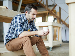 Sad carpenter drinking coffee