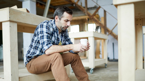 Sad carpenter drinking coffee
