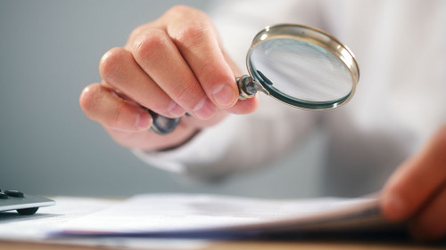 Businessman with magnifying glass reading documents