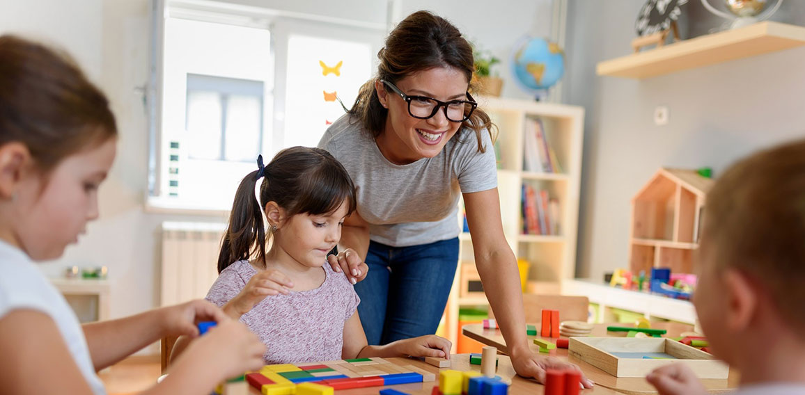 Preschool teacher with children playing with colorful wooden did