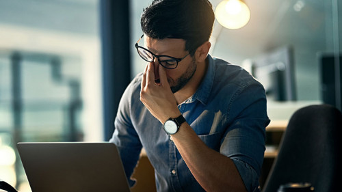 Burnout is killing his career. Shot of a young businessman experiencing stress during a late night at work.