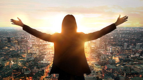 Young woman looking at the City of London at sunset. Planning th