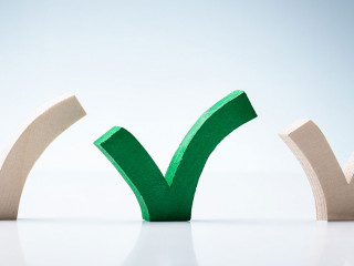 Green Check Mark Between Wooden Check Marks On Desk