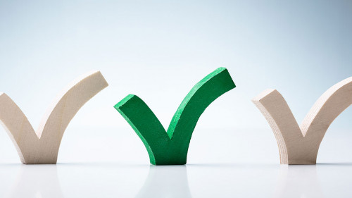 Green Check Mark Between Wooden Check Marks On Desk