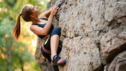 Beautiful Woman Climbing on the Rock in the Mountains. Adventure and Extreme Sport Concept