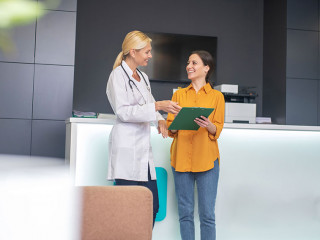 Blond doctor helping in white robe talking to patient