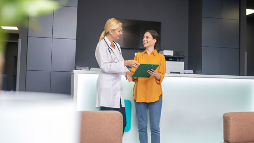 Blond doctor helping in white robe talking to patient