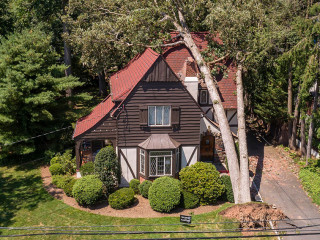 The aftermath of a dangerous wind in a suburb. A tree has fallen on a house in a small town in New Jersey after a storm and destroyed the roof.
