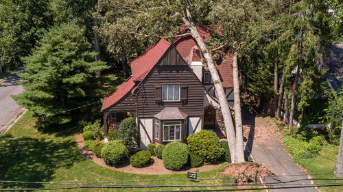 The aftermath of a dangerous wind in a suburb. A tree has fallen on a house in a small town in New Jersey after a storm and destroyed the roof.