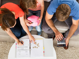 Family Sitting On Sofa Calculating Bill