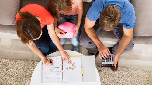Family Sitting On Sofa Calculating Bill