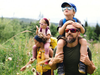 Family with small children hiking outdoors in summer nature.