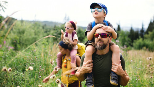 Family with small children hiking outdoors in summer nature.