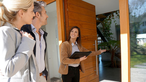 Real estate agent inviting couple to enter house for visit