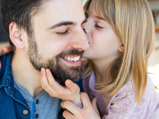 Loving little girl embrace and kissing her father in the kitchen