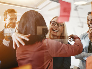 Businesswomen hugging while brainstorming with their team in an