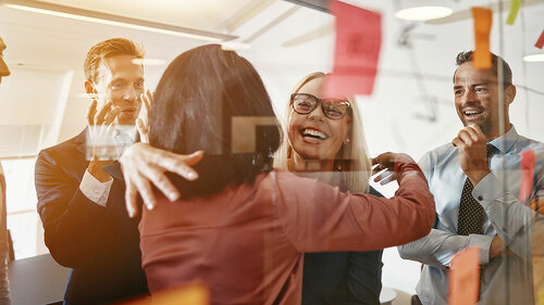 Businesswomen hugging while brainstorming with their team in an