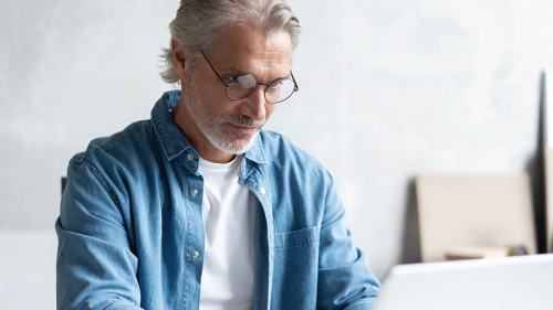 Middle-aged man working from home-office on laptop.