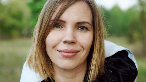 Middle-aged woman in a jacket on the street in the park.
