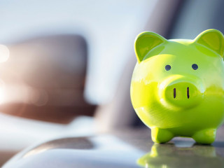 Green piggy bank money box on top of car hood, new vehicle purch