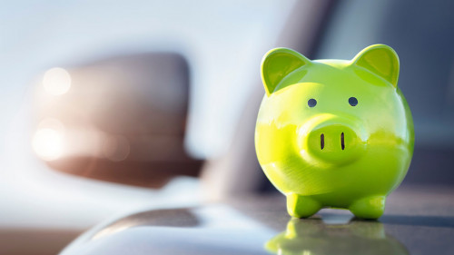Green piggy bank money box on top of car hood, new vehicle purch