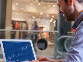 Investor analyzing stock market with charts on screen at restaur