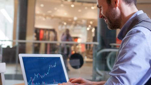 Investor analyzing stock market with charts on screen at restaur