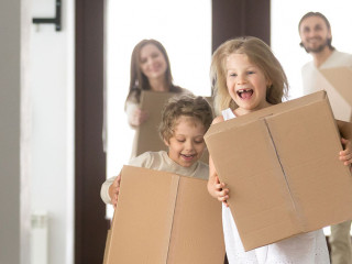 Couple and little kids with boxes running into new house