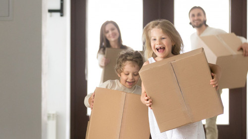 Couple and little kids with boxes running into new house